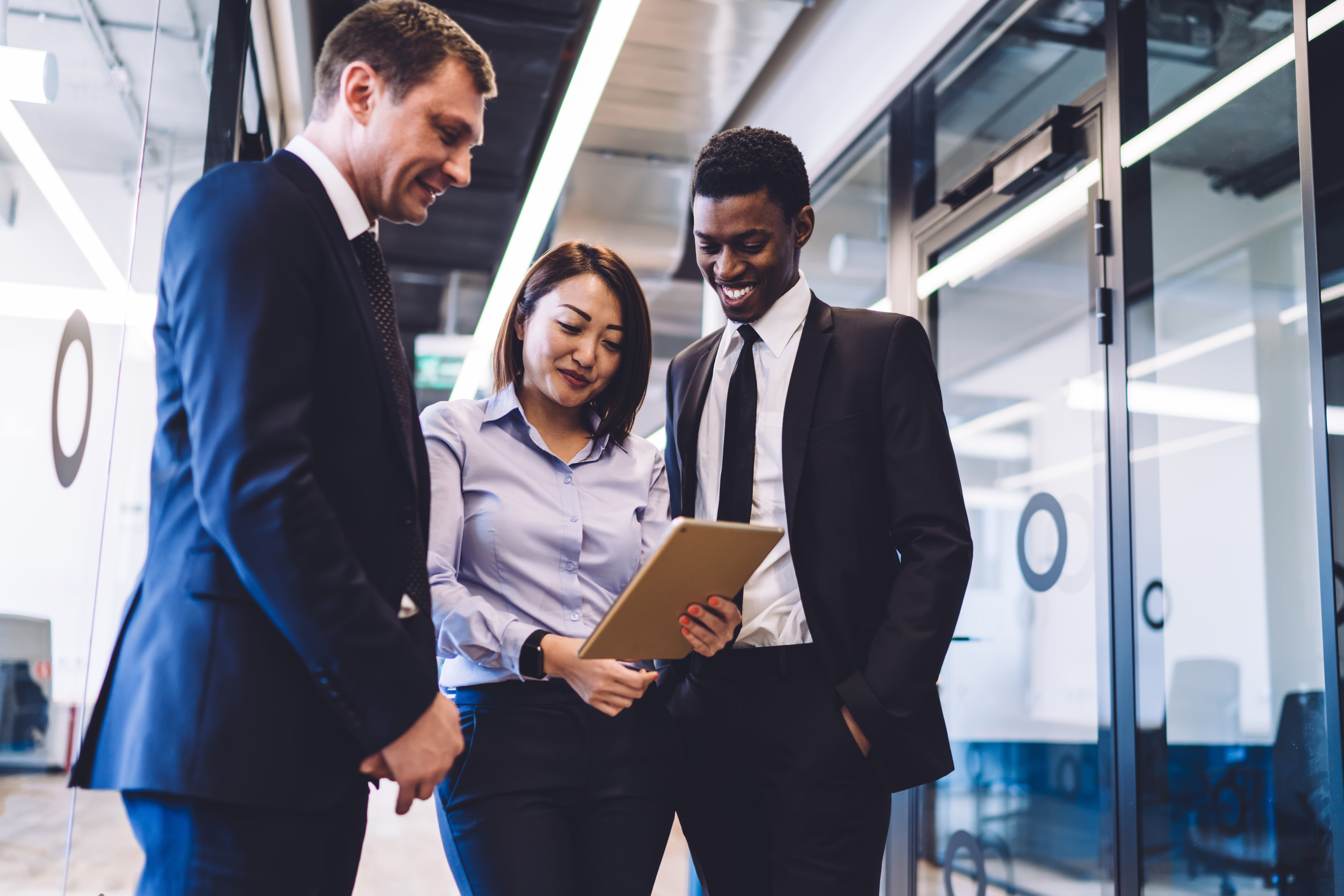 Three business professionals sharing a tablet to easily view complaints Ai in pms